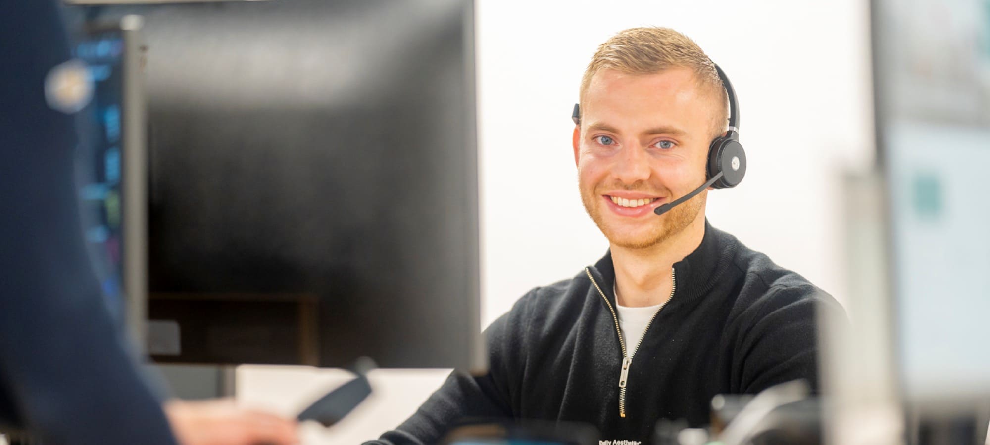 Een medewerker van ReviewRain met een headset lacht naar de camera