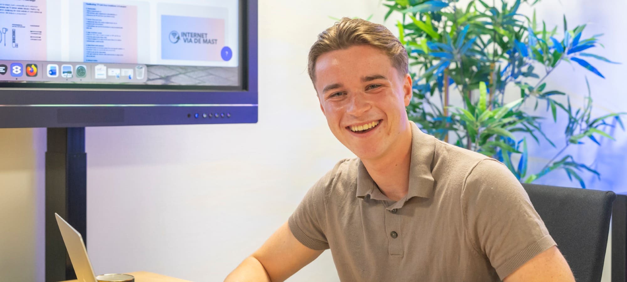 Een adviseur van ReviewRain lacht aan zijn bureau met een laptop